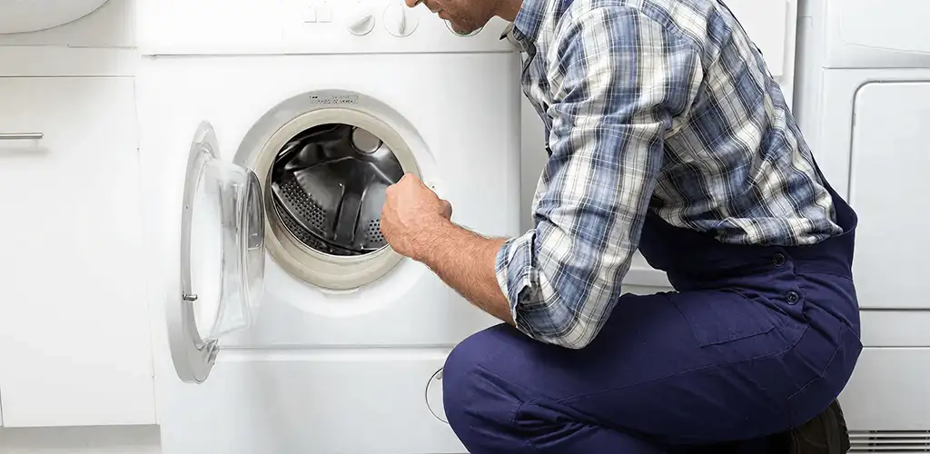 Handyman inspecting a dryer drum and internal parts for repair in Dallas, TX