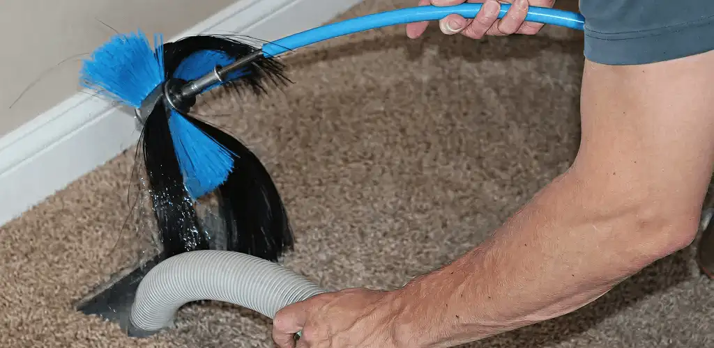 Dryer vent cleaning technician brushing lint from a vent line in Dallas, TX