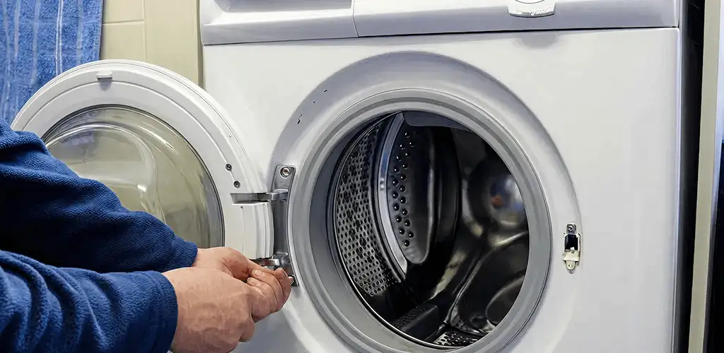 Washing machine repair handyman checking a front-load washer door and latch in Dallas, TX