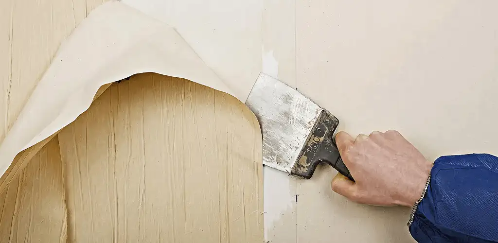Handyman removing wallpaper with a scraper for wall preparation in Dallas, TX