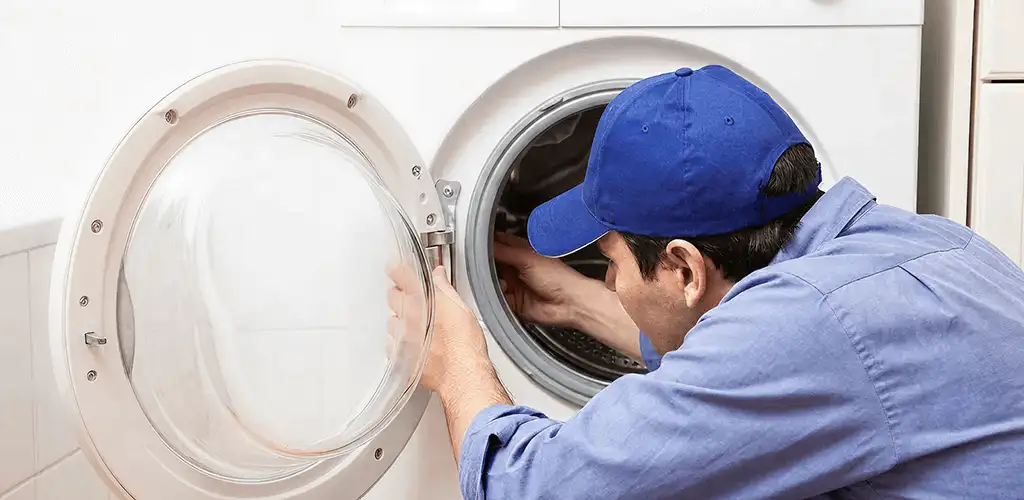 Washing machine repair handyman inspecting a front-load washer drum in Dallas, TX