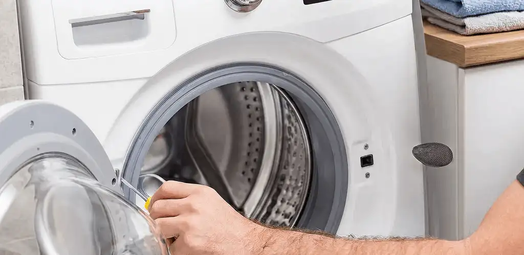 Handyman repairing a front-load washing machine and inspecting the drum in Dallas, TX