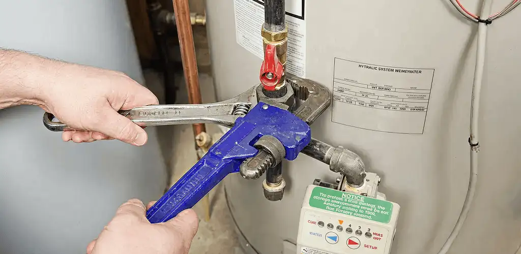 Water heater repair technician tightening the shutoff valve and supply line in Dallas, TX